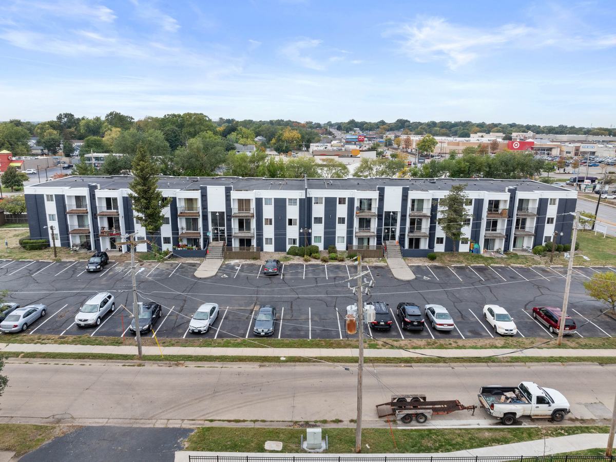 Aerial view of the property with its parking lot in front and the Merle Hay retail corridor, its stores and parking lots, spread out behind it.