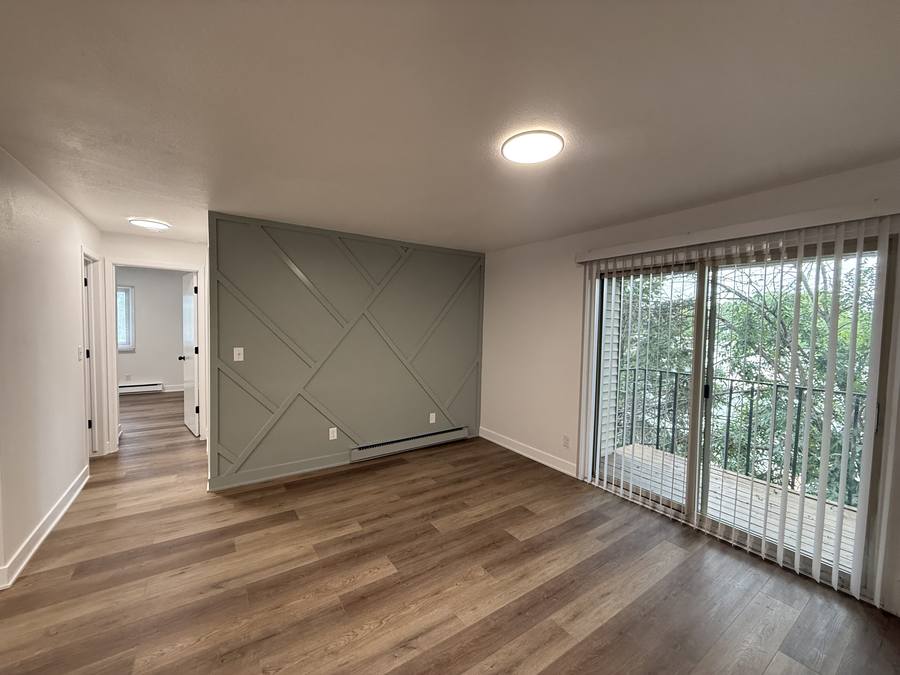 A renovated living room with an accent wall and a sliding glass door leading out to the balcony.