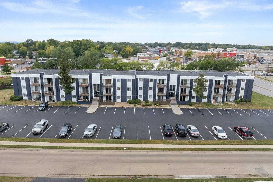 The full length of the three-story building, repainted white and slate grey, above a freshly striped parking lot.
